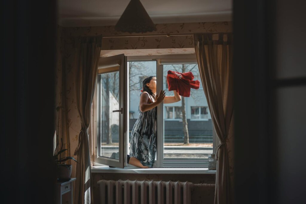 woman cleaning her window in the attic 